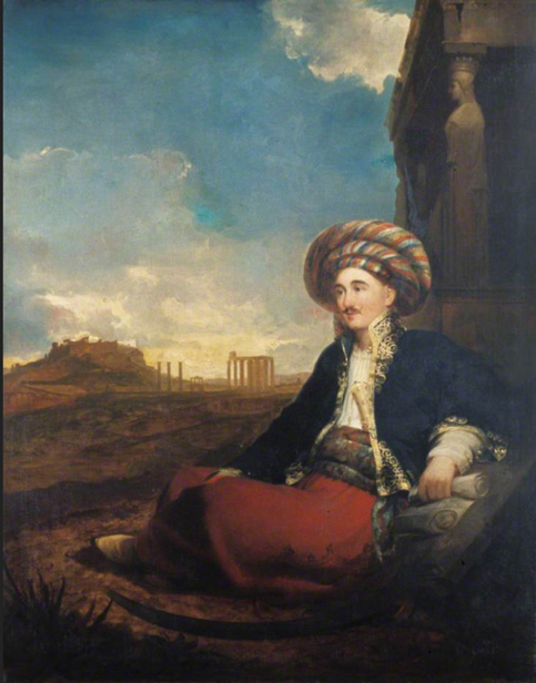 Robert Wilson reclining in a middle eastern outfit, with temple ruins on the far horizon behind him