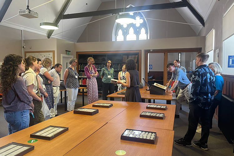 Attendees standing around a meeting table, in discussion.